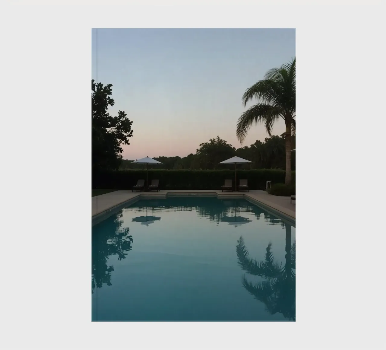 Swimming Pool Reflecting Palm Trees and Umbrellas at Dusk notebook by DesignDoodle