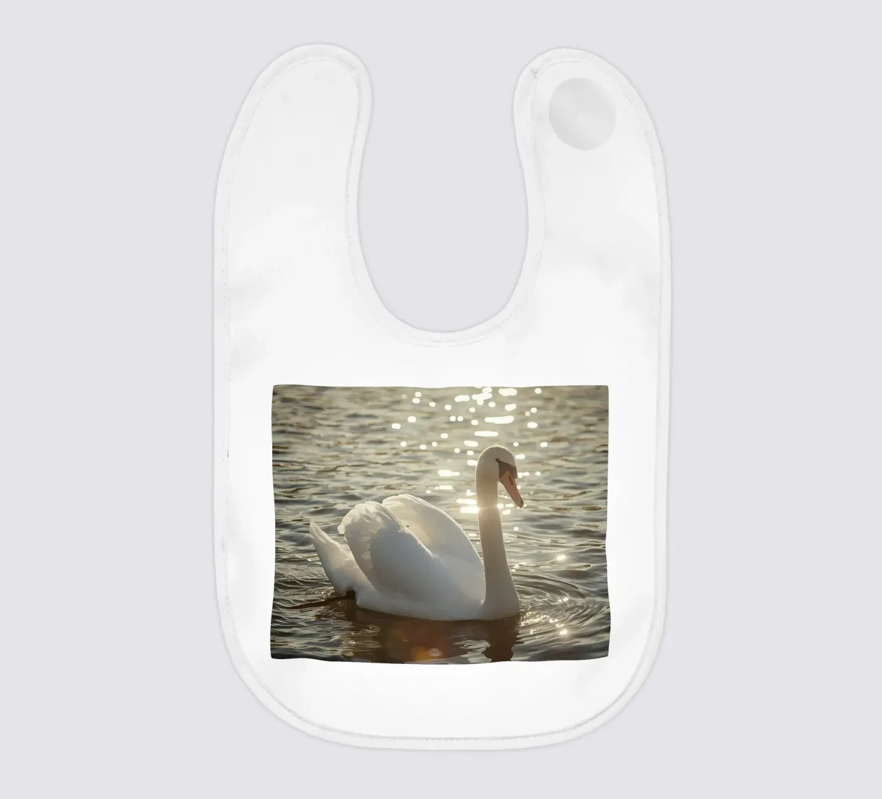Cigno bianco sull'acqua con riflessi di luce solare bavaglino da DesignDoodle