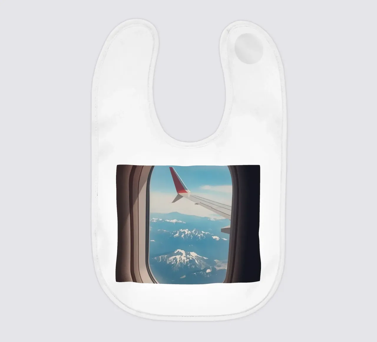Vue d'un hublot d'avion sur une aile et des montagnes bavoir de DesignDoodle