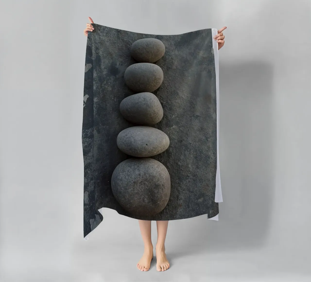 Cinque pietre grigie impilate verticalmente su una superficie strutturata telo mare da DesignDoodle