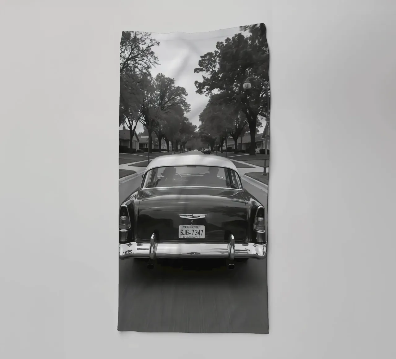 Vue arrière d'une voiture classique dans une rue en noir et blanc serviette de bain de DesignDoodle