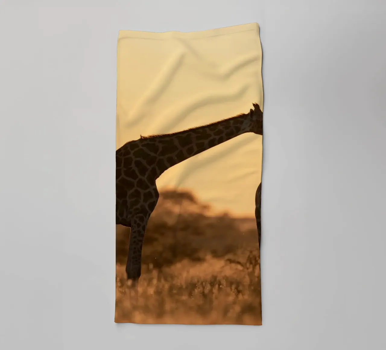 A giraffe standing on the meadow in the afternoon towel by Earthly Visions