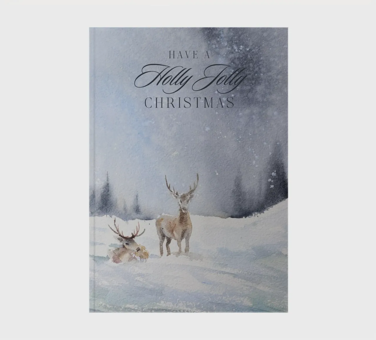 Reindeer in a winter forest with the lettering Have a Holly Jolly Chr notebook by Studio Vibe