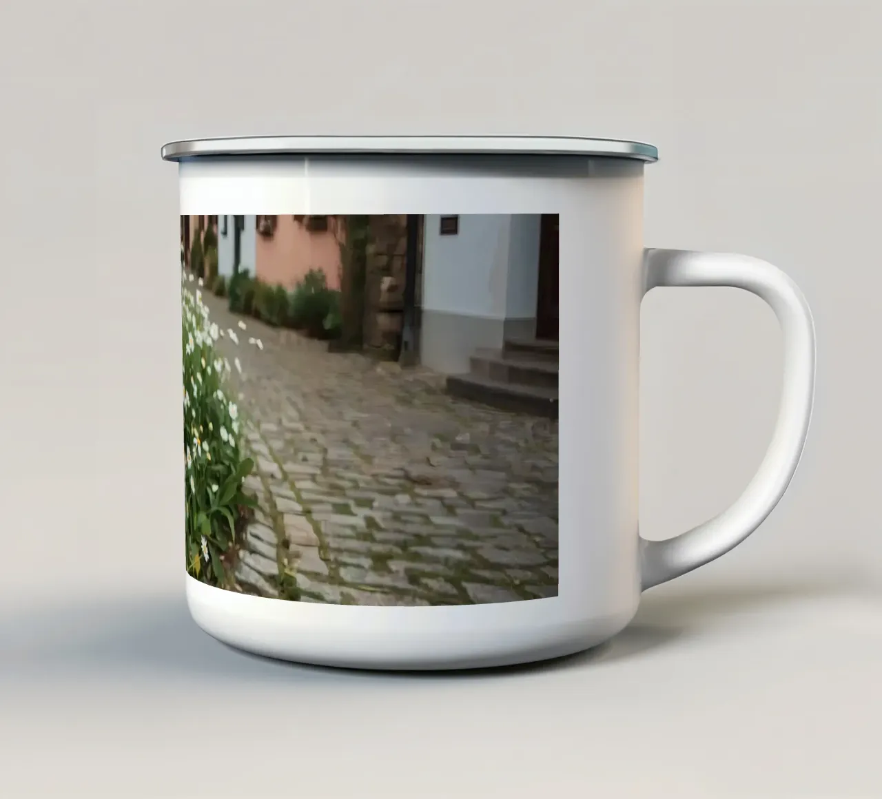 Margherite lungo una strada acciottolata con edifici tazza in smalto da DesignDoodle