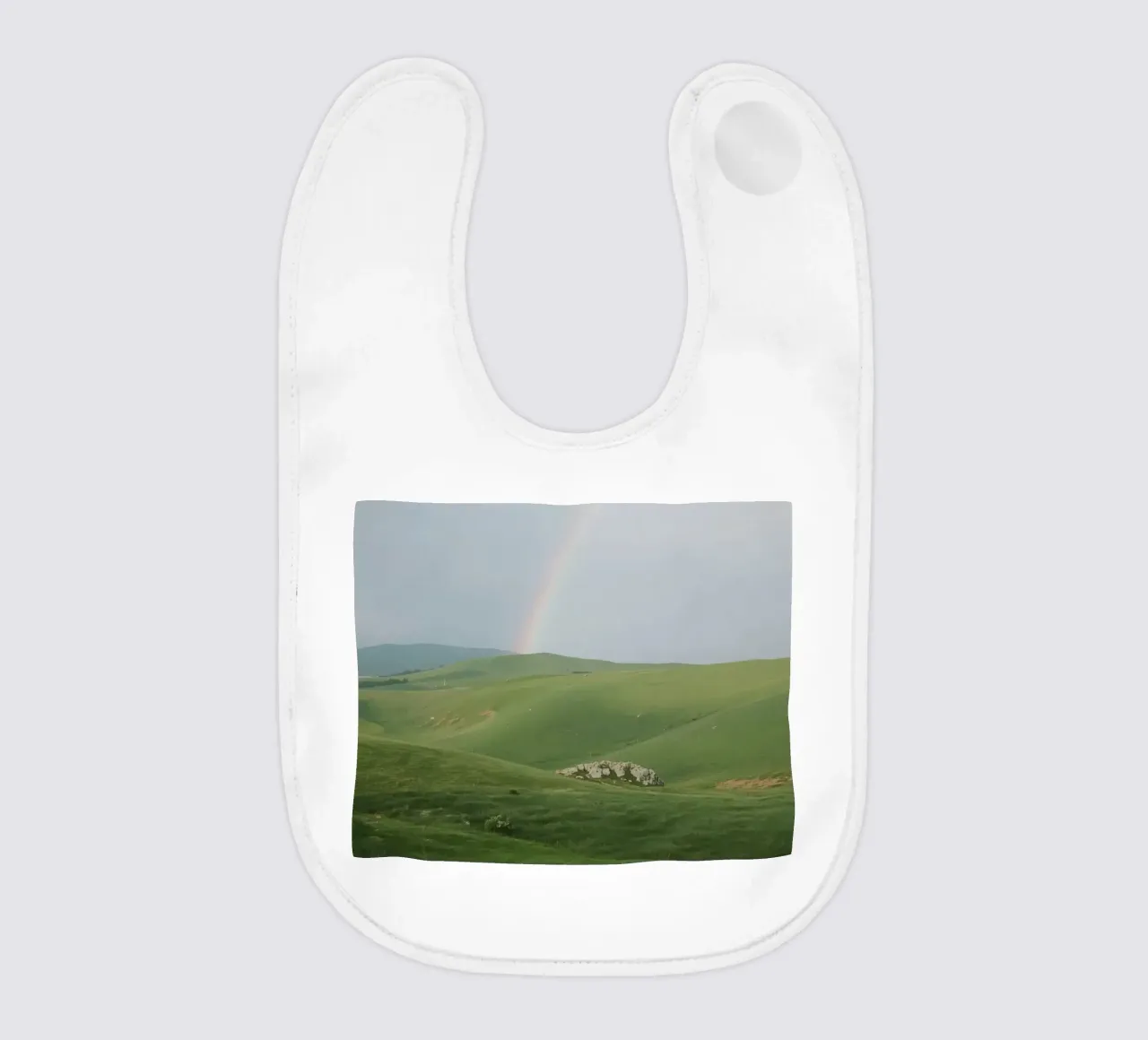 Colline verdi con arcobaleno e rocce bavaglino da DesignDoodle