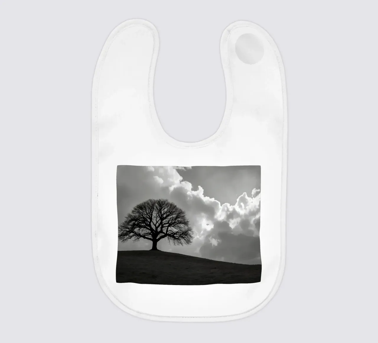 Sagoma di un albero spoglio su una collina contro un cielo nuvoloso bavaglino da DesignDoodle
