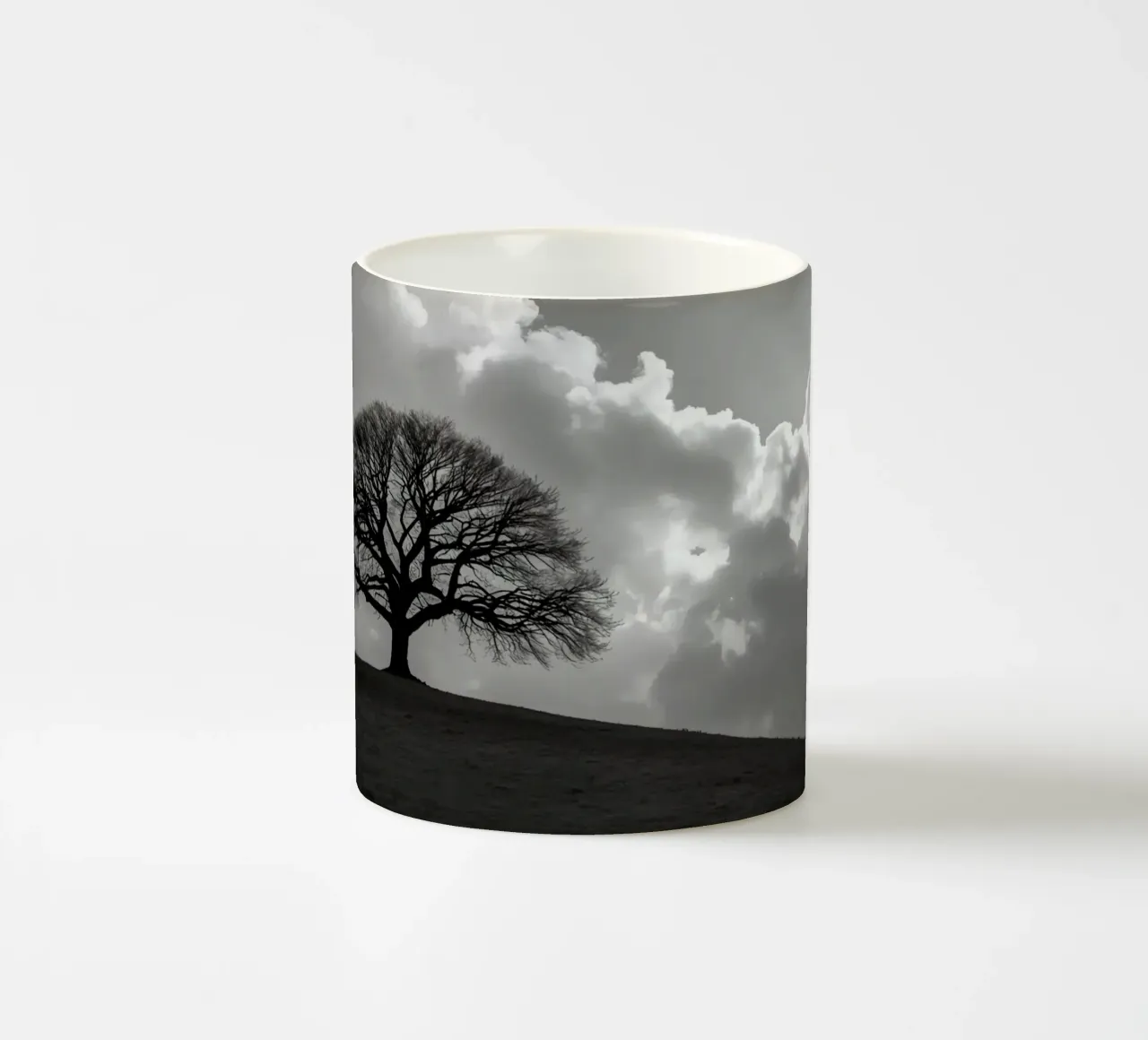 Sagoma di un albero spoglio su una collina contro un cielo nuvoloso tazza in ceramica da DesignDoodle