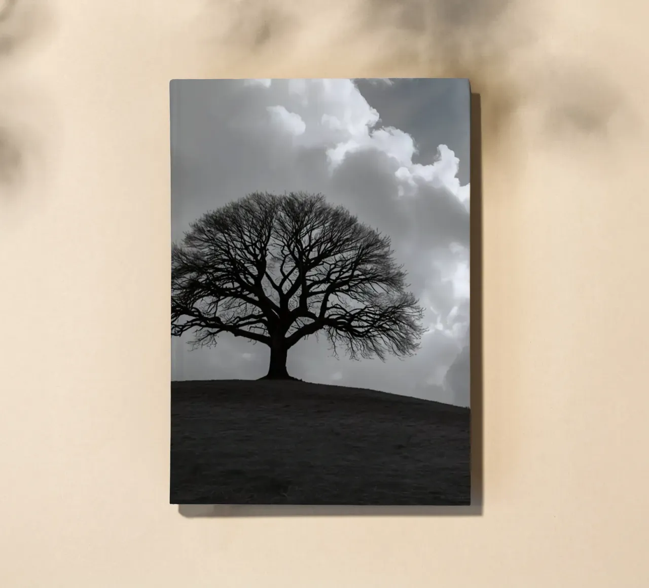 Silhouette of a bare tree on a hill against a cloudy sky notebook by DesignDoodle
