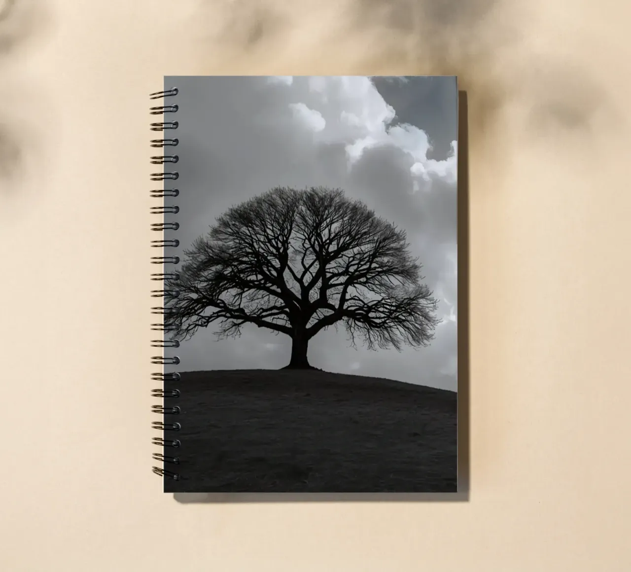 Silhouette of a bare tree on a hill against a cloudy sky spiral notebook by DesignDoodle