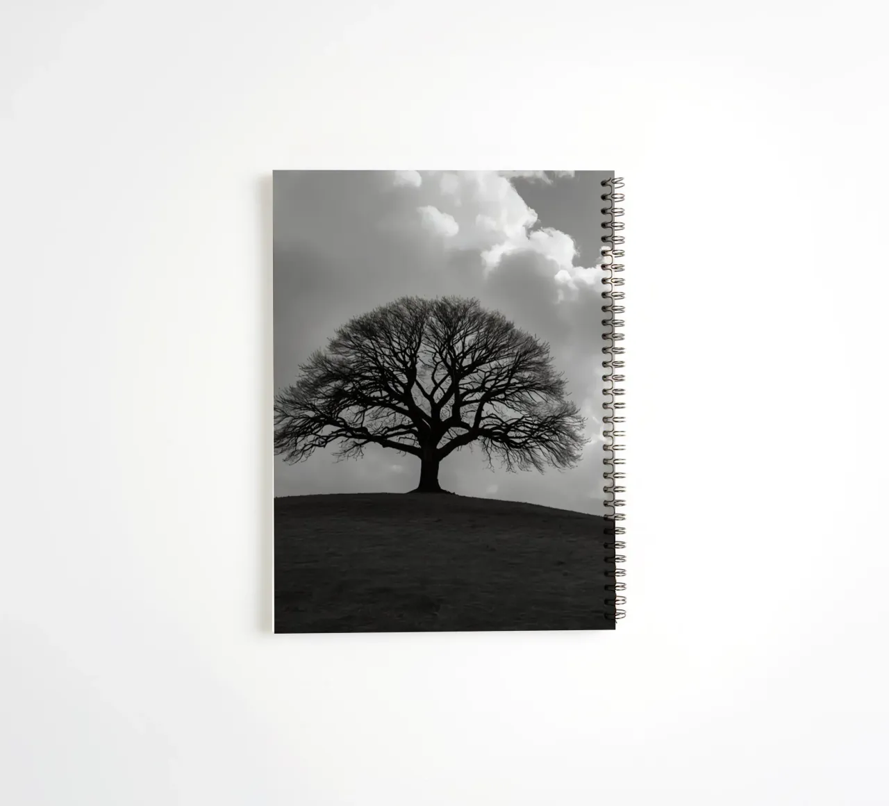 Silhouette of a bare tree on a hill against a cloudy sky spiral notebook by DesignDoodle