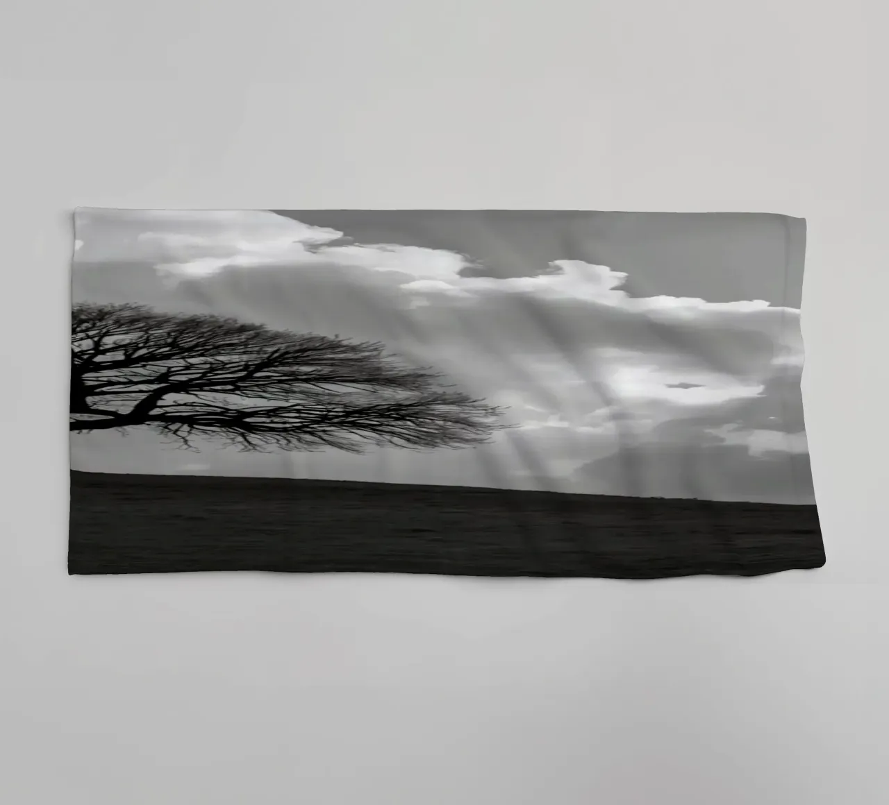 Silhouette of a bare tree on a hill against a cloudy sky towel by DesignDoodle