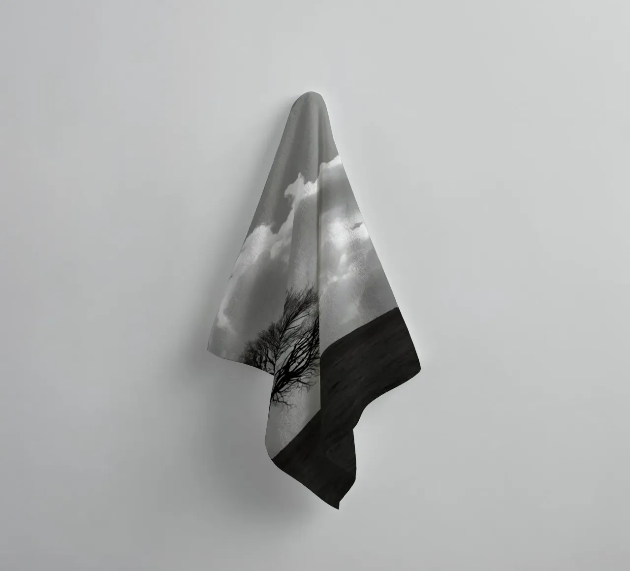 Silhouette of a bare tree on a hill against a cloudy sky towel by DesignDoodle