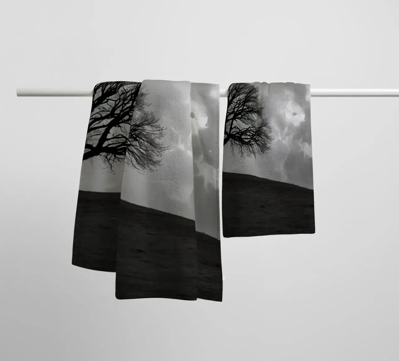 Silhouette of a bare tree on a hill against a cloudy sky towel by DesignDoodle