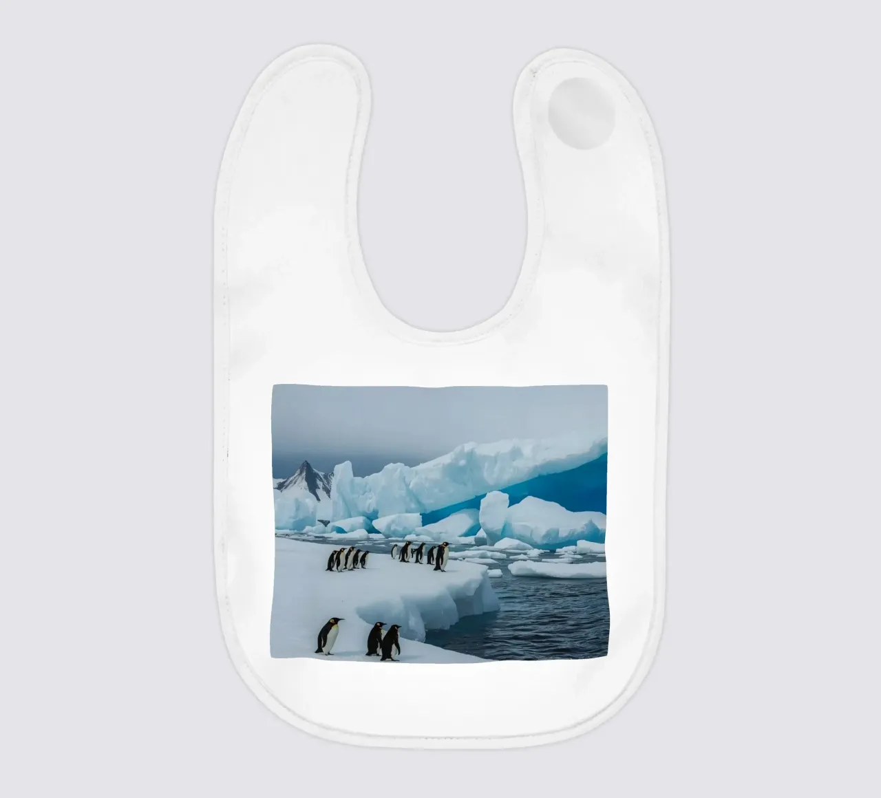 Pinguini imperatore su una distesa di ghiaccio con iceberg e montagne bavaglino da DesignDoodle