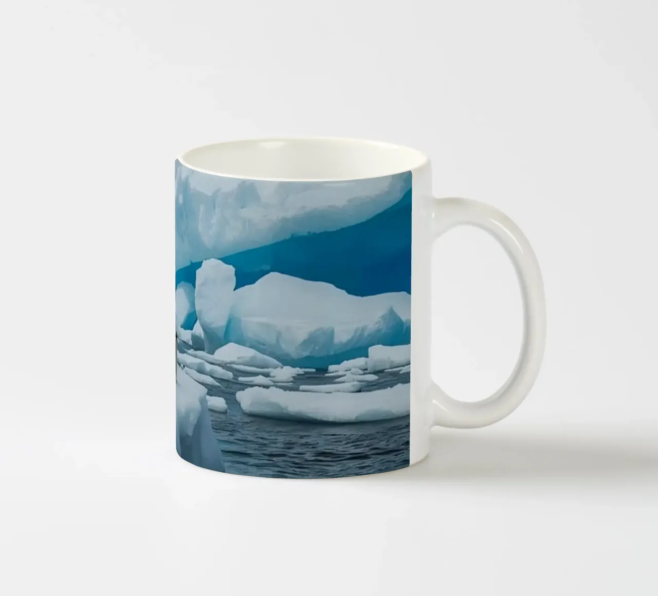 Pinguini imperatore su una distesa di ghiaccio con iceberg e montagne tazza in ceramica da DesignDoodle