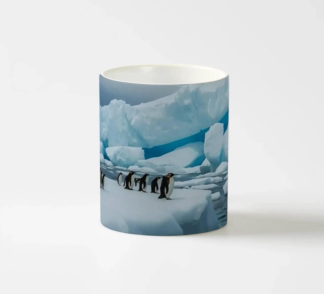 Pinguini imperatore su una distesa di ghiaccio con iceberg e montagne tazza in ceramica da DesignDoodle