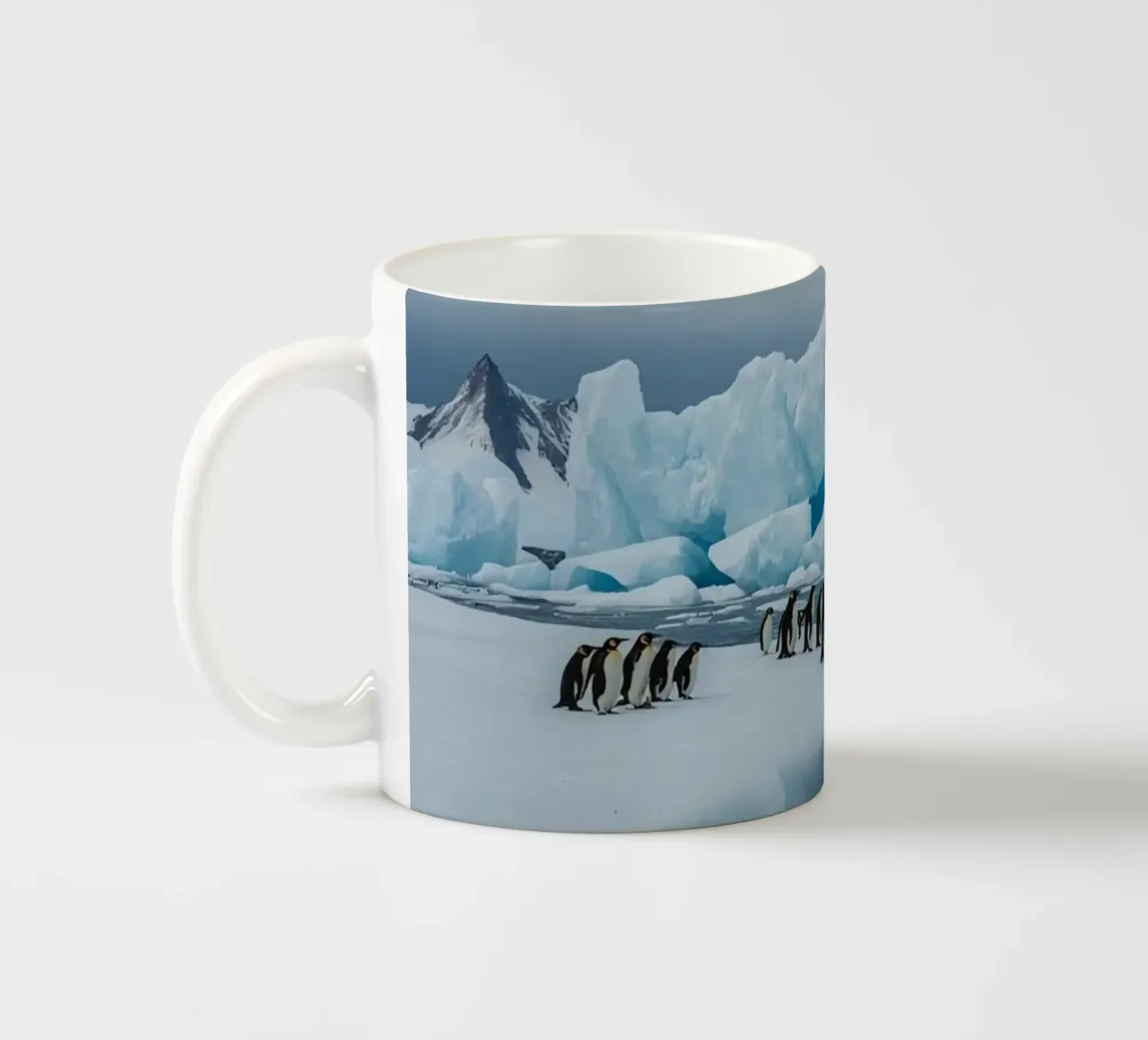 Pinguini imperatore su una distesa di ghiaccio con iceberg e montagne tazza in ceramica da DesignDoodle