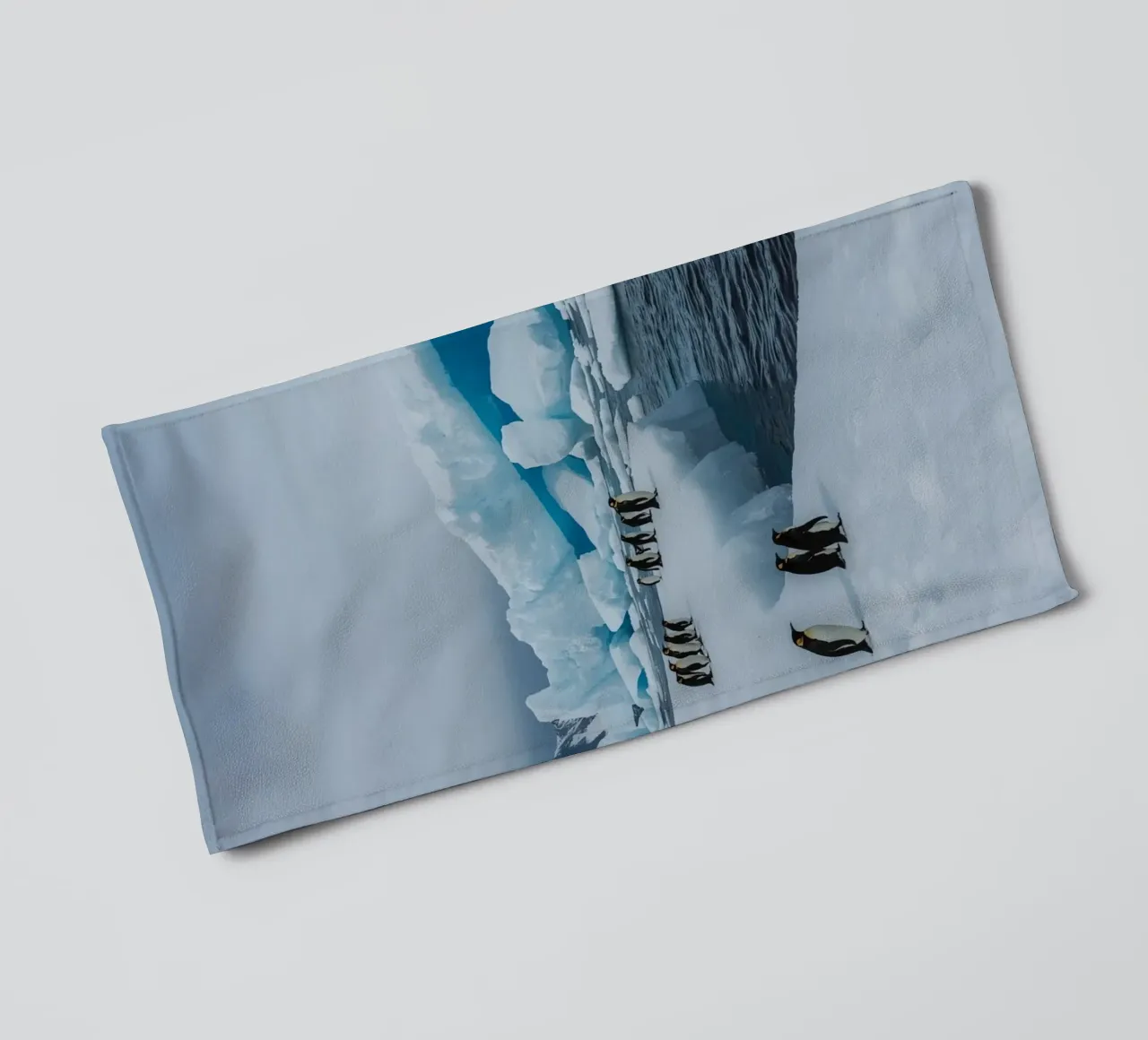 Pinguini imperatore su una distesa di ghiaccio con iceberg e montagne asciugamano da bagno da DesignDoodle