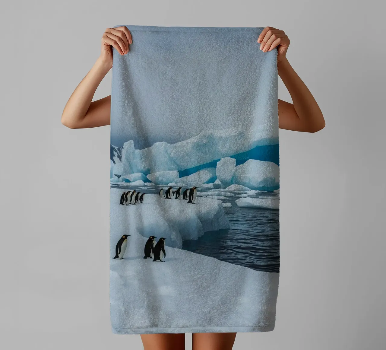 Pinguini imperatore su una distesa di ghiaccio con iceberg e montagne asciugamano da bagno da DesignDoodle
