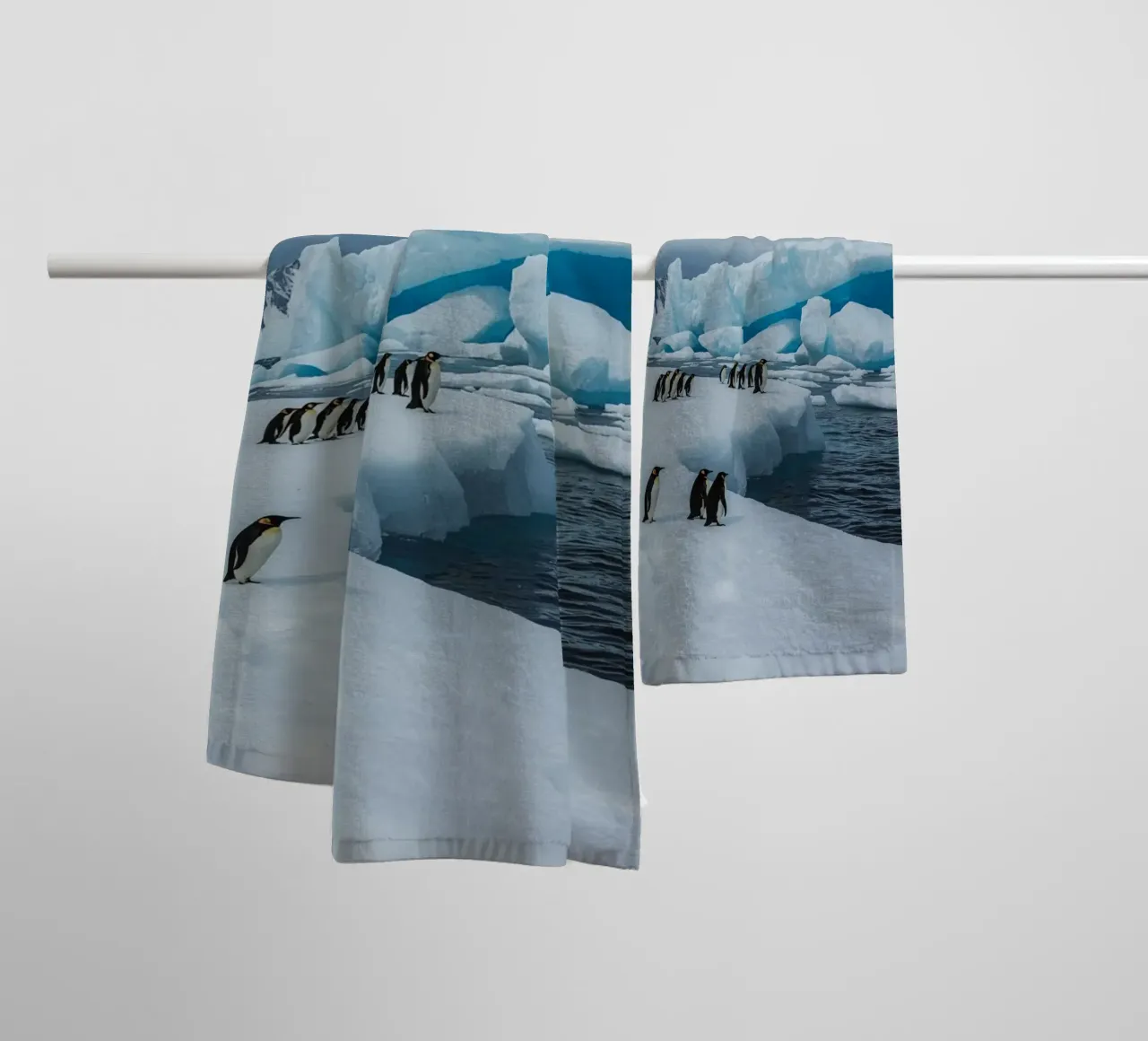Pinguini imperatore su una distesa di ghiaccio con iceberg e montagne asciugamano da bagno da DesignDoodle
