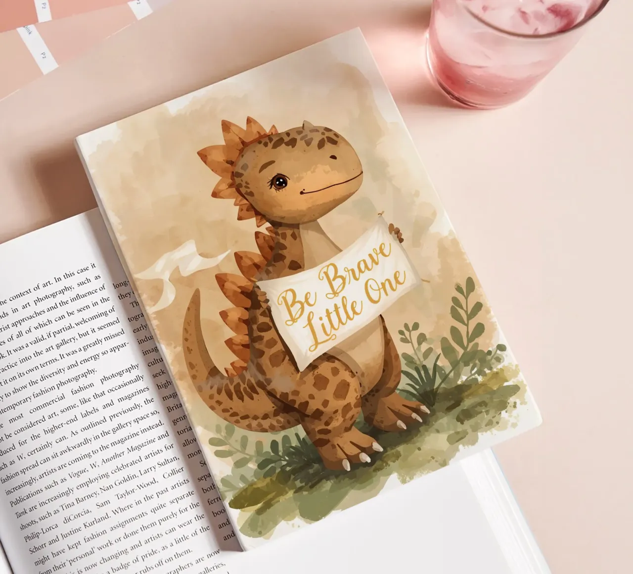 Un simpatico dinosauro con in mano lo striscione "Be Brave Little One". diario da DesignDoodle