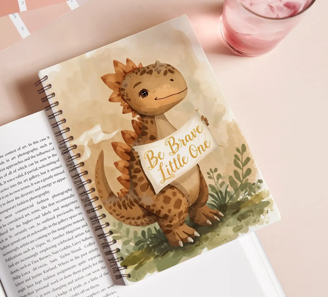 Un simpatico dinosauro con in mano lo striscione "Be Brave Little One". diario ad anelli da DesignDoodle