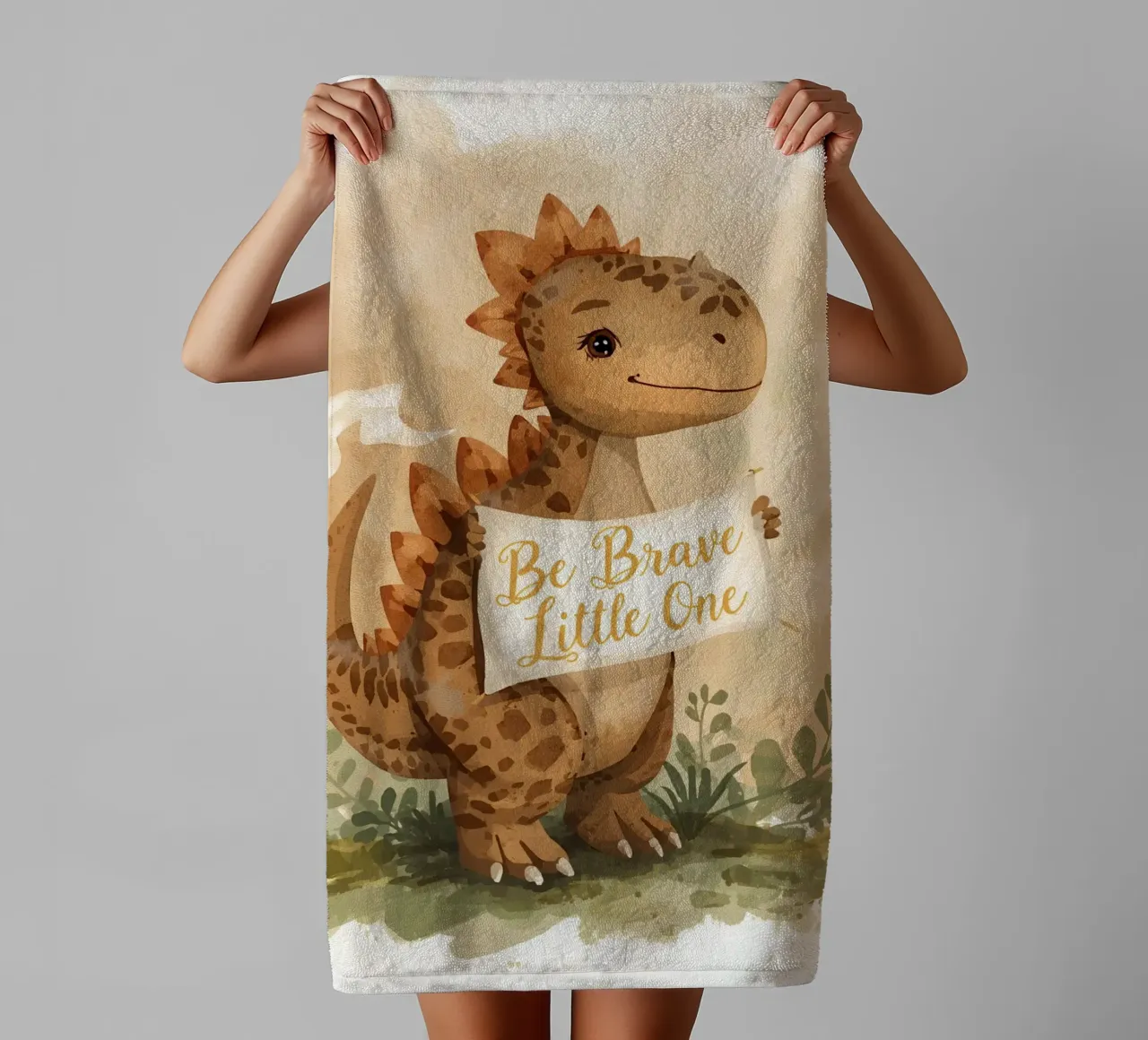 Un simpatico dinosauro con in mano lo striscione "Be Brave Little One". asciugamano da bagno da DesignDoodle