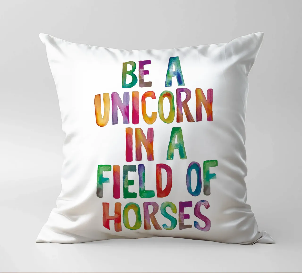 Essere un unicorno in un campo di cavalli Tipografia arcobaleno cuscino da THE MOTIVATED TYPE