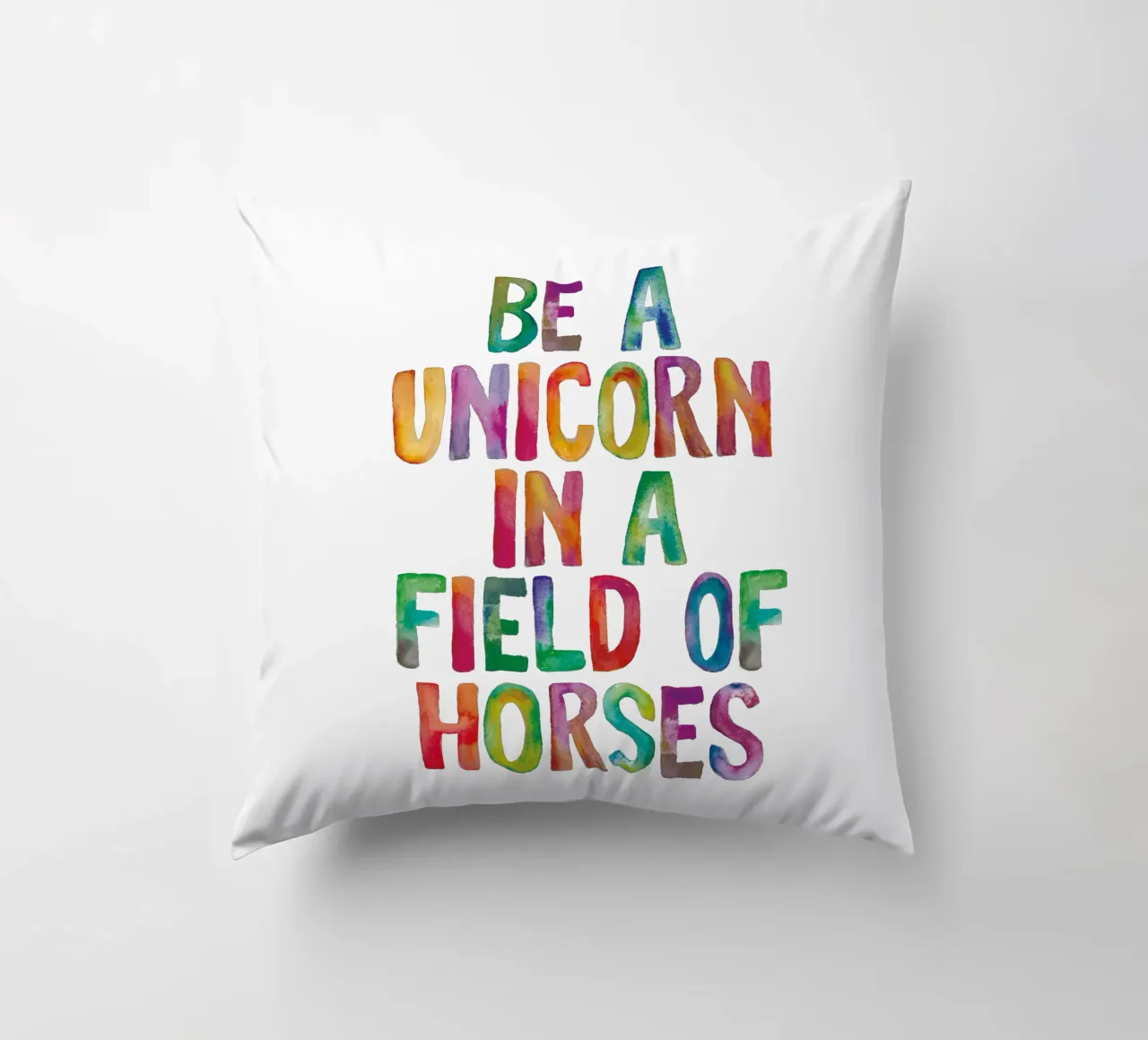 Essere un unicorno in un campo di cavalli Tipografia arcobaleno cuscino da THE MOTIVATED TYPE