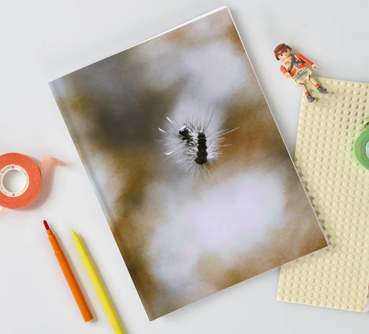 Black, floating caterpillar in front of brown background, analogue notebook by Lisa Jureczko Arts Illustration