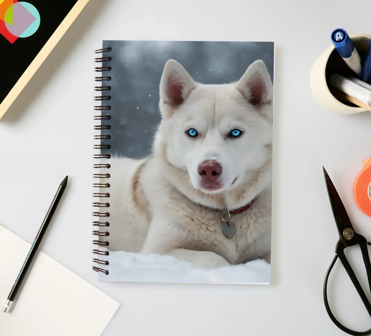 Husky dog with striking blue eyes resting in soft white snow spiral notebook by DesignDoodle