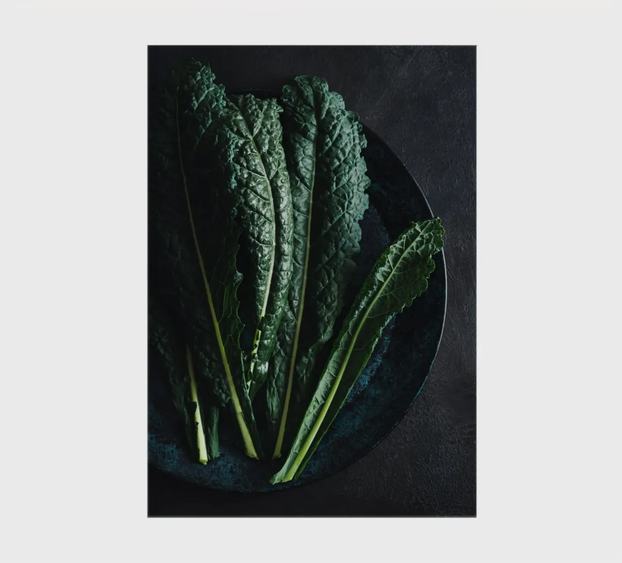 Foglie di cavolo riccio su un piatto di colore scuro diario da foodphotolove