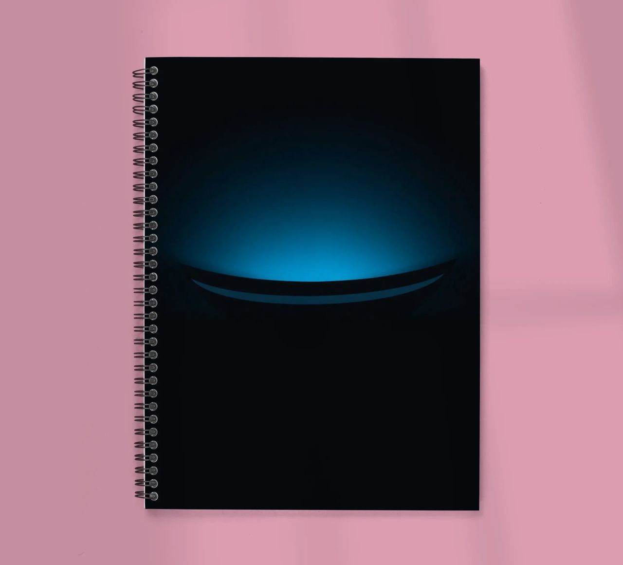 Subtle blue glow illuminating a curved surface in a dark set spiral notebook by DesignDoodle