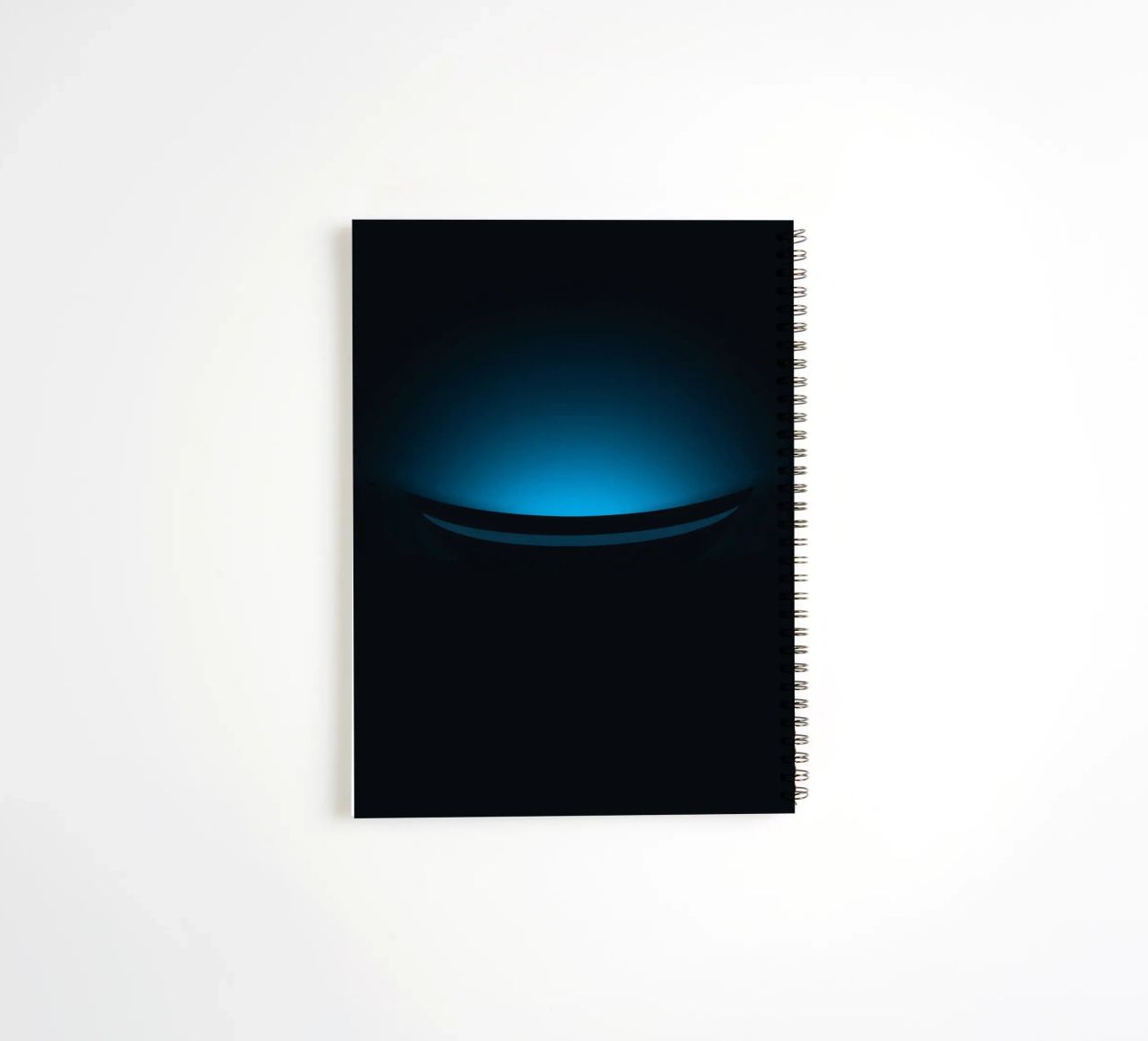 Subtle blue glow illuminating a curved surface in a dark set spiral notebook by DesignDoodle