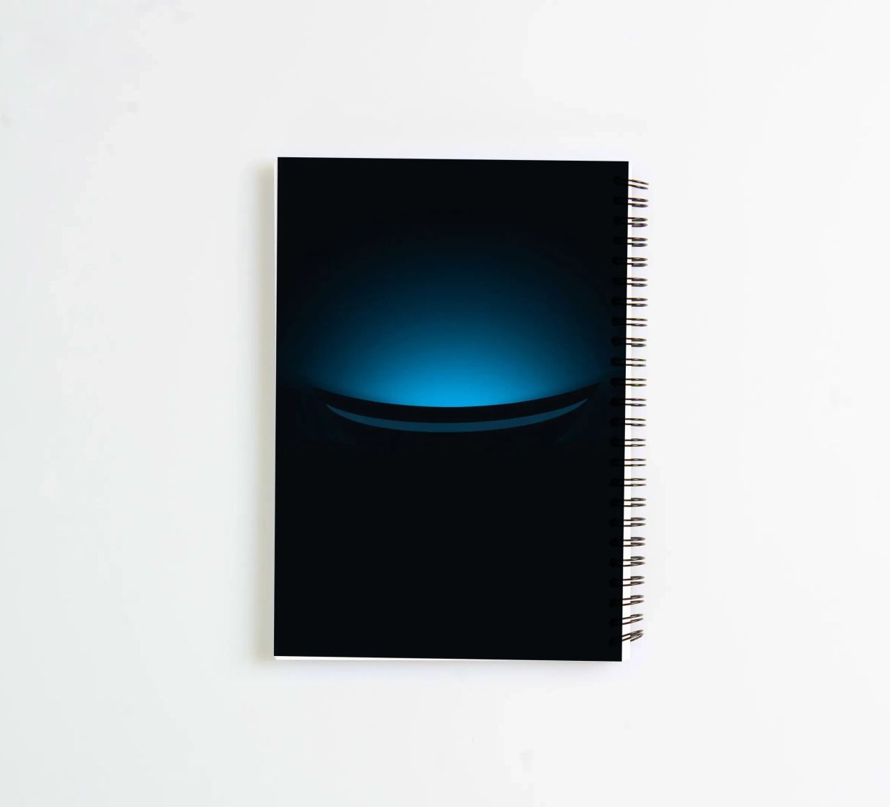 Subtle blue glow illuminating a curved surface in a dark set spiral notebook by DesignDoodle